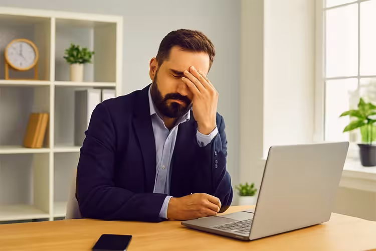 تصویر مردی خسته پشت لپ تاپ